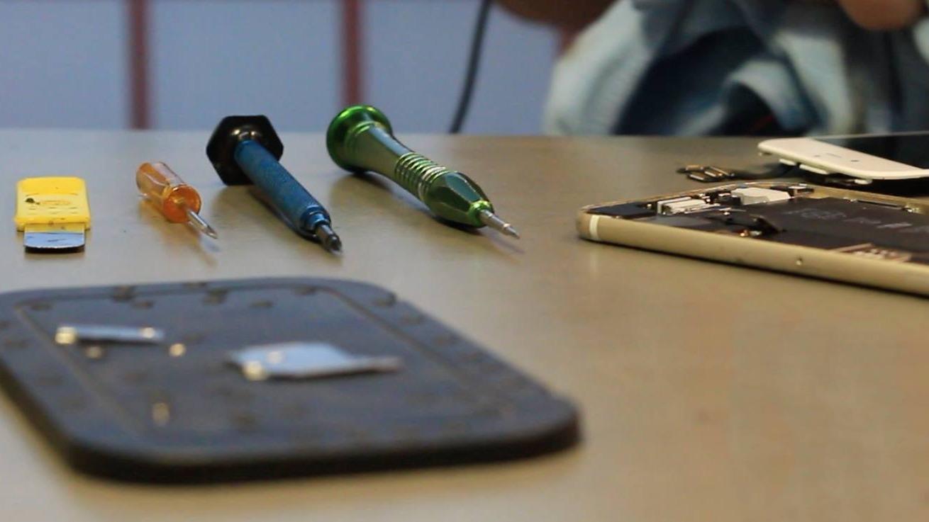 Værktøj til reparation af elektronik, herunder skruetrækkere og en kniv, ligger på et bord.