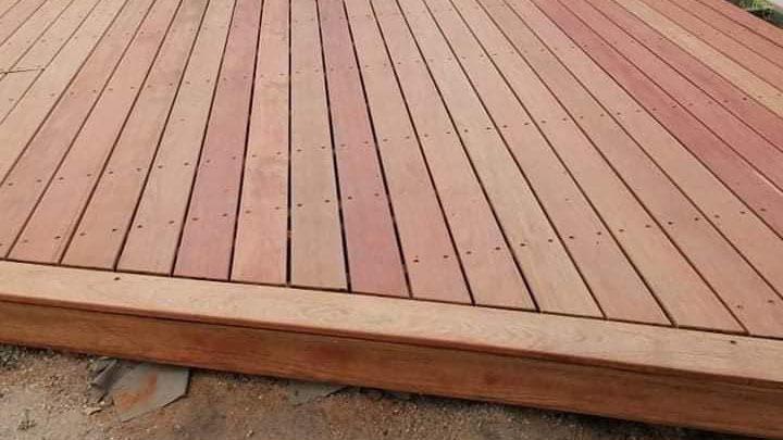 Ny træterrasse med glatte planker i forskellige nuancer af rød og brun, klar til brug.