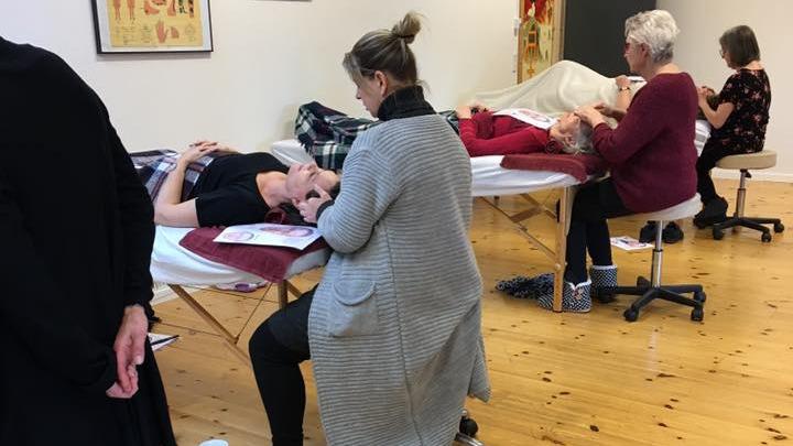 Fire personer deltager i en undervisningssession om ansigtsbehandlinger i et lyst lokale.