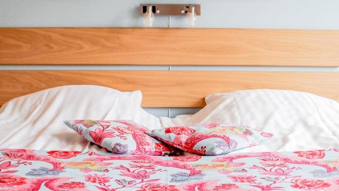 Seng med bløde puder og farverigt sengetøj i en moderne indretning.