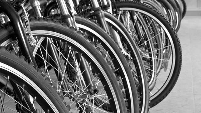 Række af cykler med fokus på dæk og fælge i sort-hvidt.
