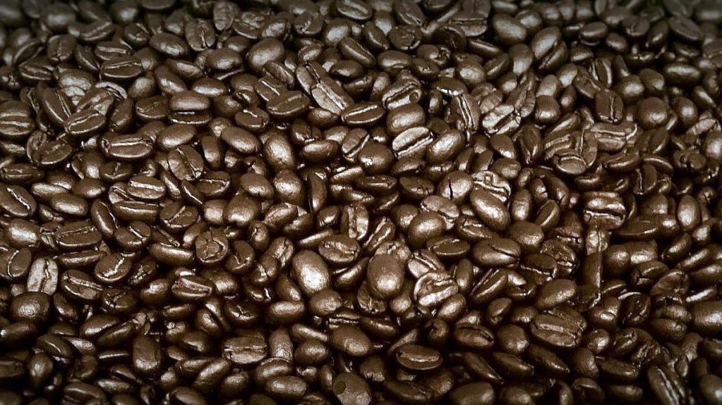 En tæt samling af mørkristede kaffebønner, der viser deres glatte overflade og rige farve.