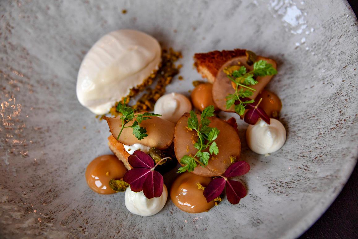 En elegant tallerken med dessert bestående af is, kager, chokolade, flødeskum og friske urter.
