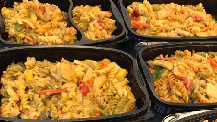 Fem sorte plastikbeholdere med pastaretter fyldt med spiralpasta, kylling, grøntsager og en cremet sauce.