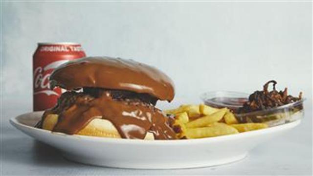 En saftig burger med chokoladefyld, pomfritter og en cola i baggrunden.