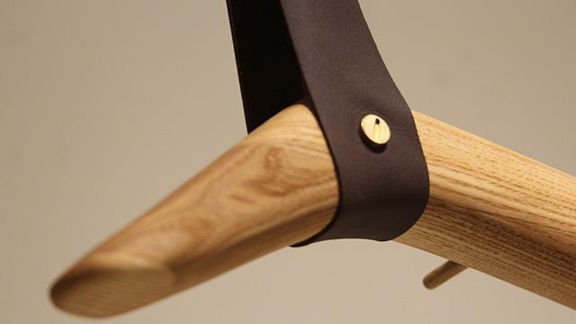 Detalje af en træknop med læderrem og metalknap, der viser håndværk og design.