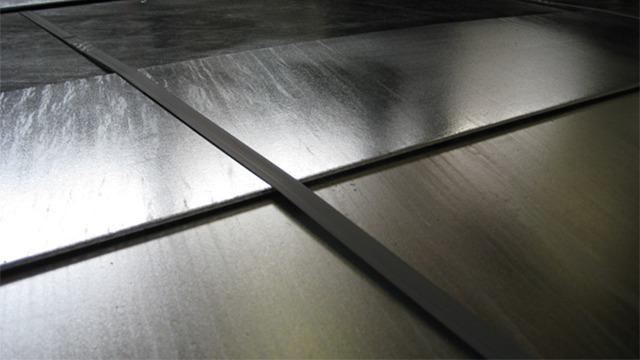 Nærbillede af metalplader med forskellige overflader og strukturer, der skaber et moderne udseende.