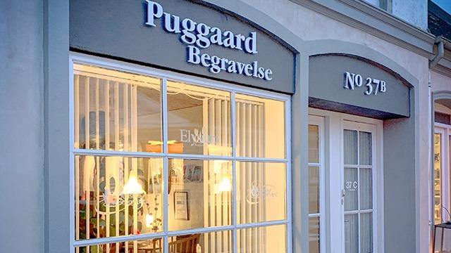 Facade af Puggaard Begravelse med vinduer og skilt, der viser nummer 37.