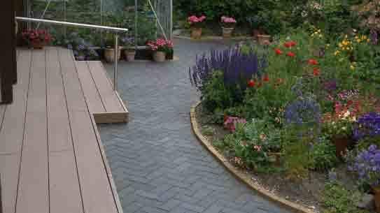 En smuk have med farverige blomster og en stenbelagt sti, der fører til en terrasse.