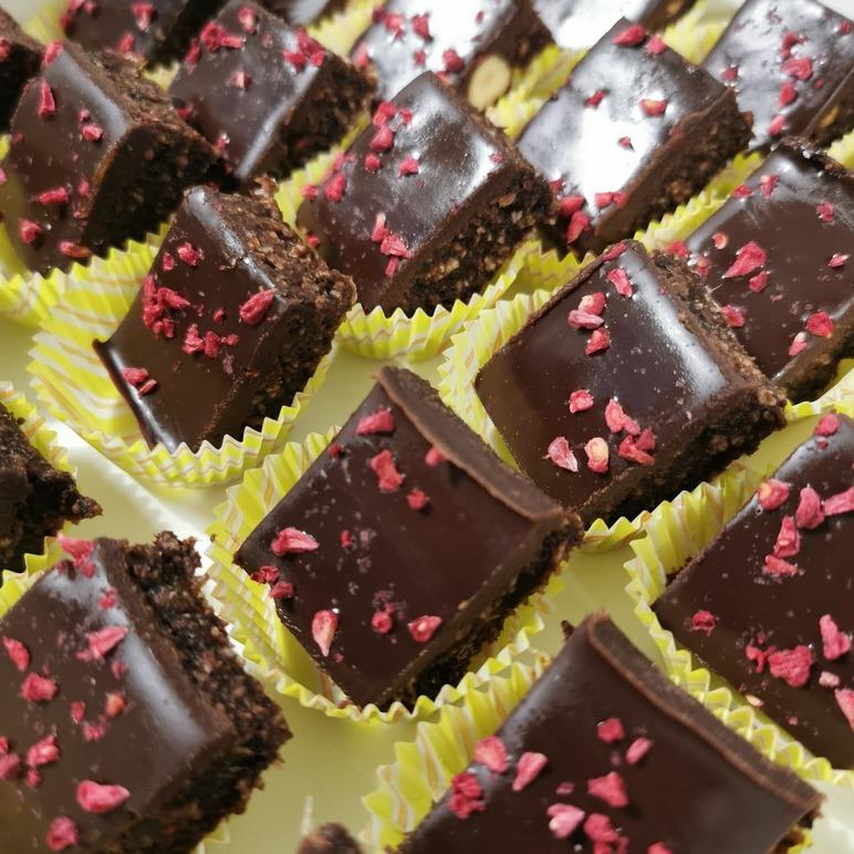 Lækre chokoladebid med hindbærstykker, præsenteret i gule papirforme.
