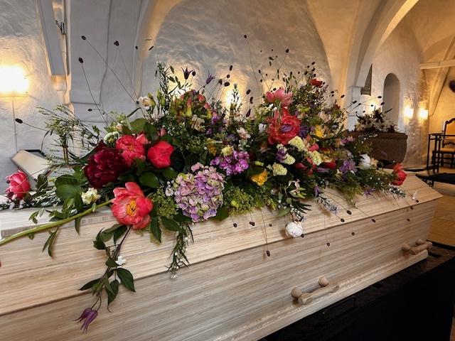 En smuk blomsterdekoration med farverige blomster som pæoner, hyacinter og roser på en lys baggrund.