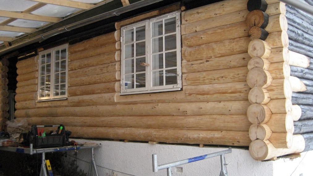 En træhytte med logvægge og vinduer, der viser en rustik og naturlig arkitektur.