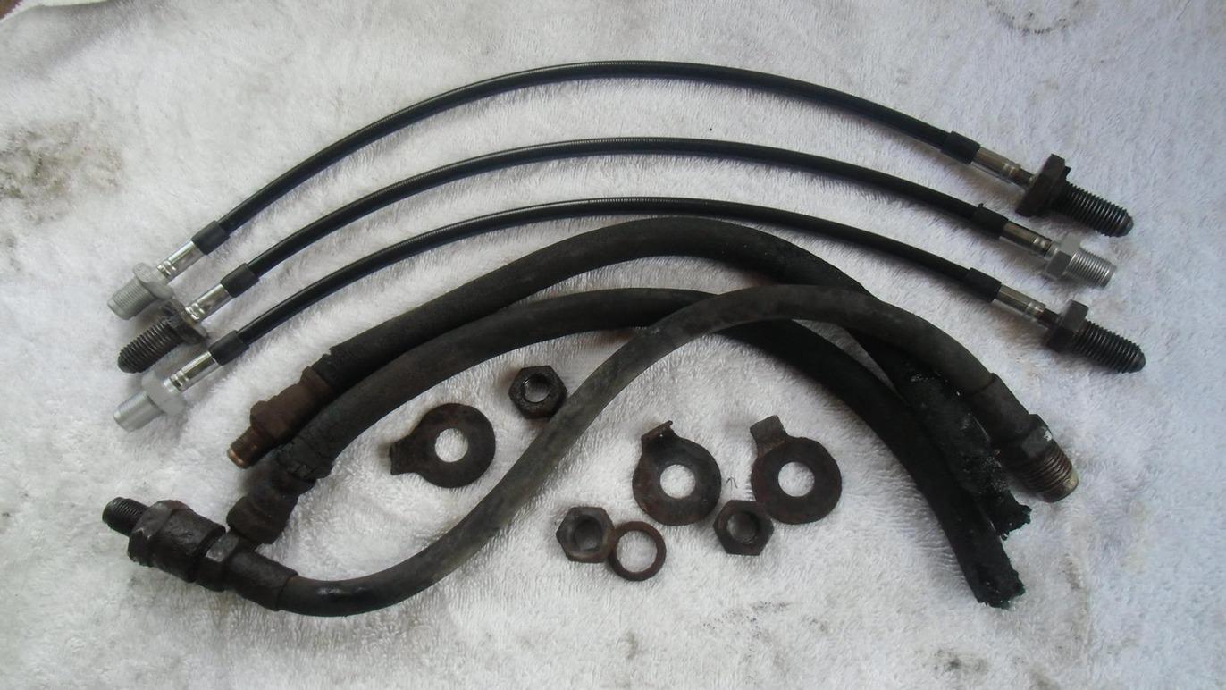 Bremserør og fittings til bilreparation, sort og metal, placeret på en hvid klud.