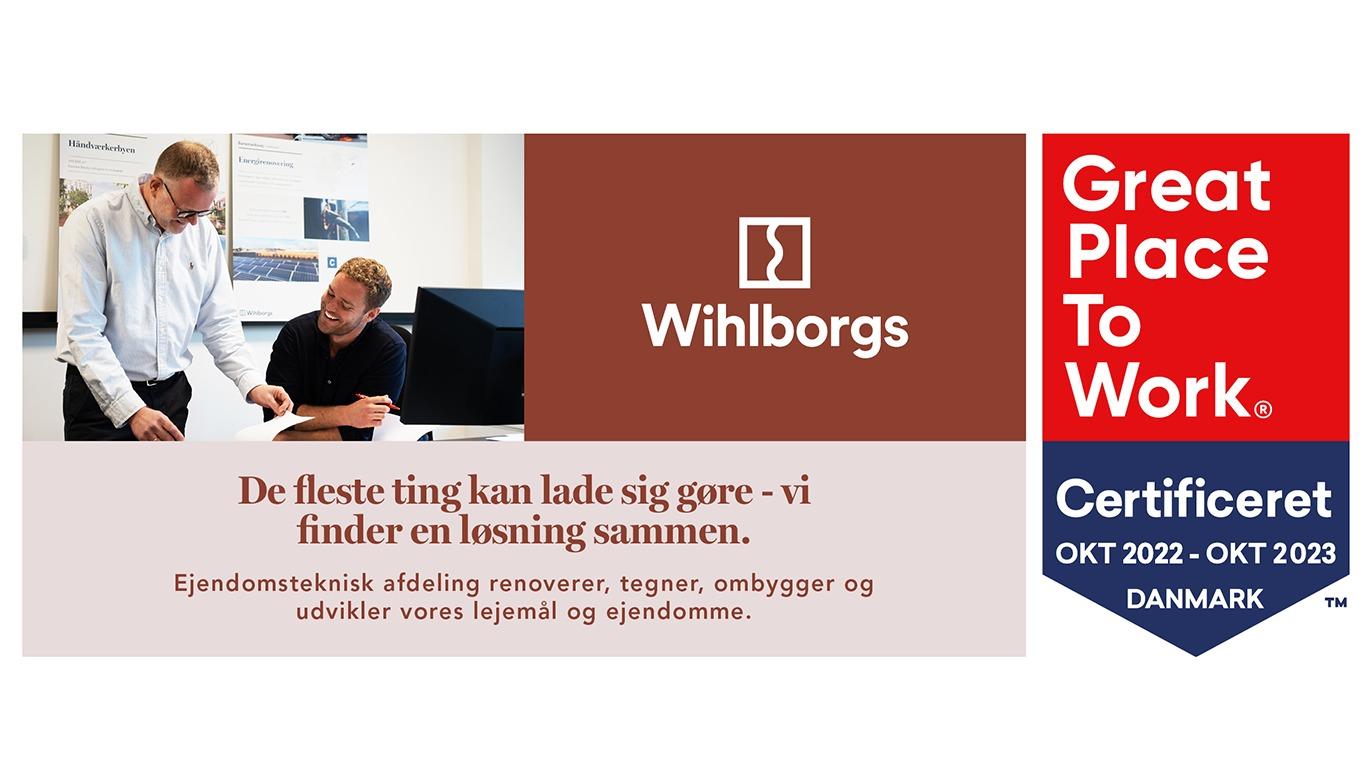 To medarbejdere diskuterer løsninger i et kontormiljø med Wihlborgs logo og certificering for "Great Place To Work".
