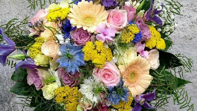 En farverig buket med roser, gerbera, krysantemum og forskellige vilde blomster.