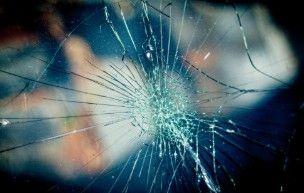 Et nærbillede af en knust glasrude med sprækker, der stråler ud fra midten.