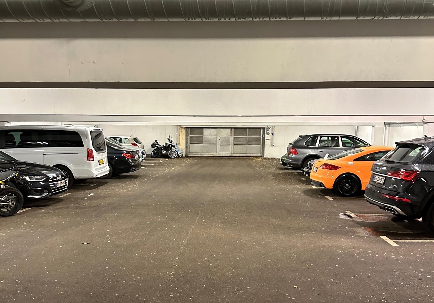 Tom parkeringsplads med flere biler og motorcykler i en underjordisk garage.