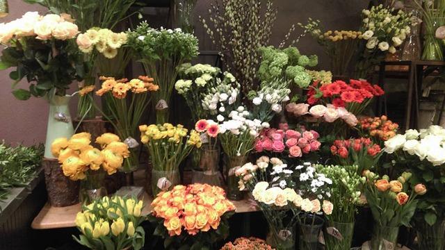 En farverig blomsterbutik med forskellige buketter af roser, tulipaner og andre blomster i glasvaser.
