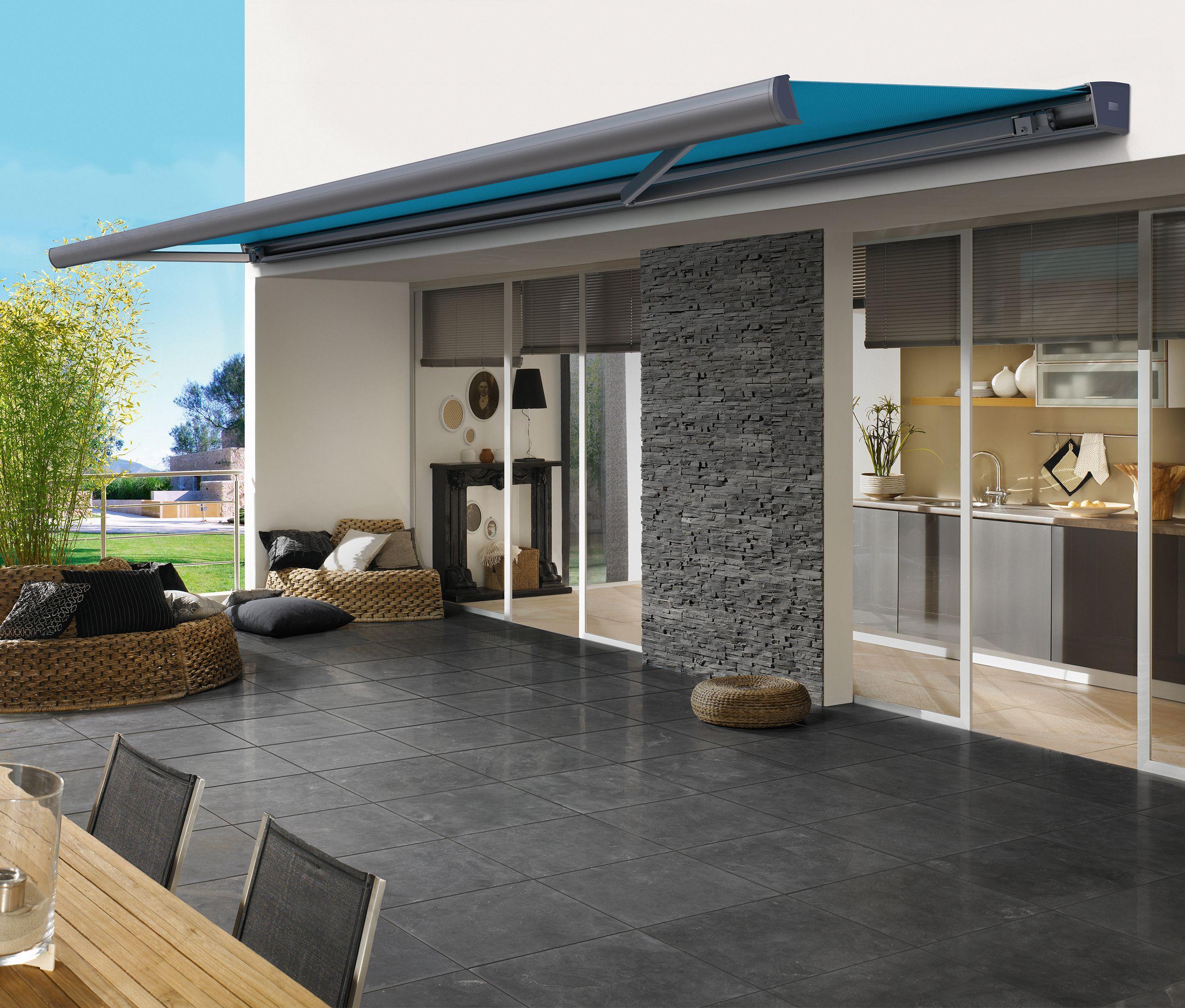 Moderne terrasse med markise, stenvæg og stilfuld indretning, der skaber en indbydende atmosfære.