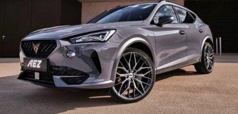 En grå SUV fra Cupra med store sorte fælge, præsenteret på en lys overflade.