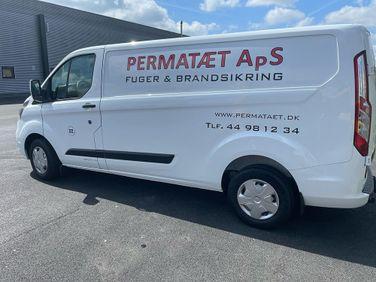Hvid varevogn med teksten "PERMATÆT ApS" og kontaktinformation på siden, parkeret på en asfaltbelagt plads.