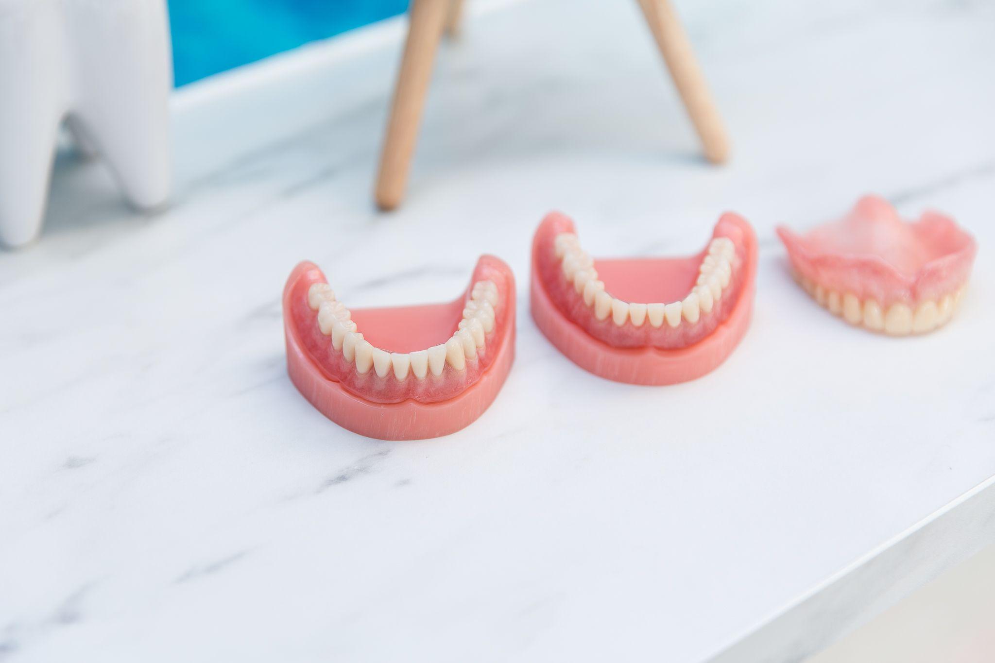 Toothmodeller i forskellige størrelser på en marmoroverflade, der viser tandproteser og tandpleje.