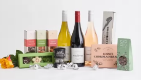 En samling af vine, chokolade og snacks præsenteret med en rose på en hvid baggrund.