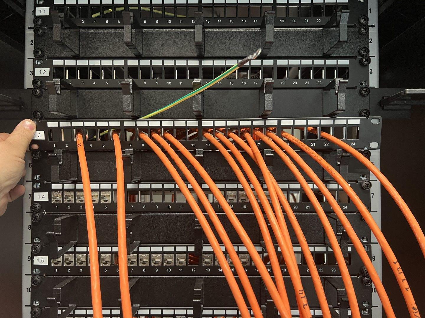 Et serverrack med orange kabler, der er tilsluttet forskellige porte og forbindelser.