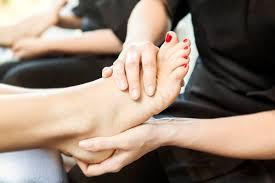 En person får en fodmassage med rød neglelak på tæerne i en afslappende salon.