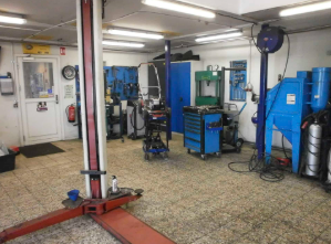 Værksted med løftebukke, værktøjsvogne og udstyr til reparation af biler.