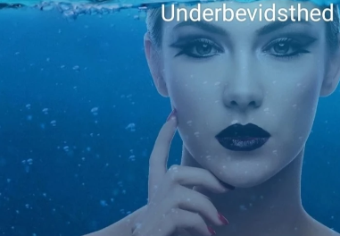 En kvinde med dramatisk makeup svømmer under vandet, omgivet af bobler og blå nuancer.