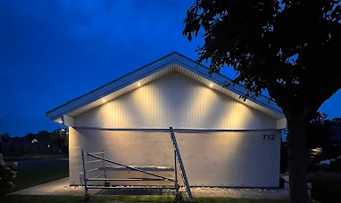 Et hus med belysning ved skumringstid, med stillads foran og nummer 712 synligt på væggen.