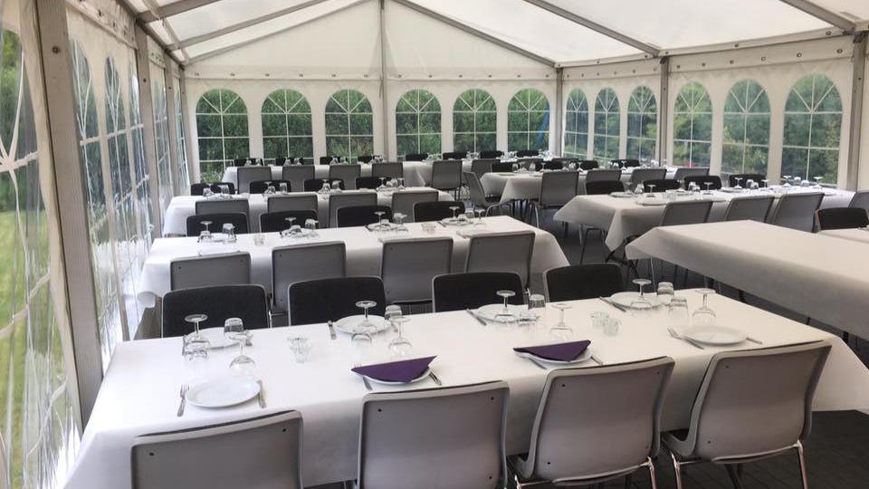 En festtelt med opdækkede borde og stole, klar til en fest eller middag.
