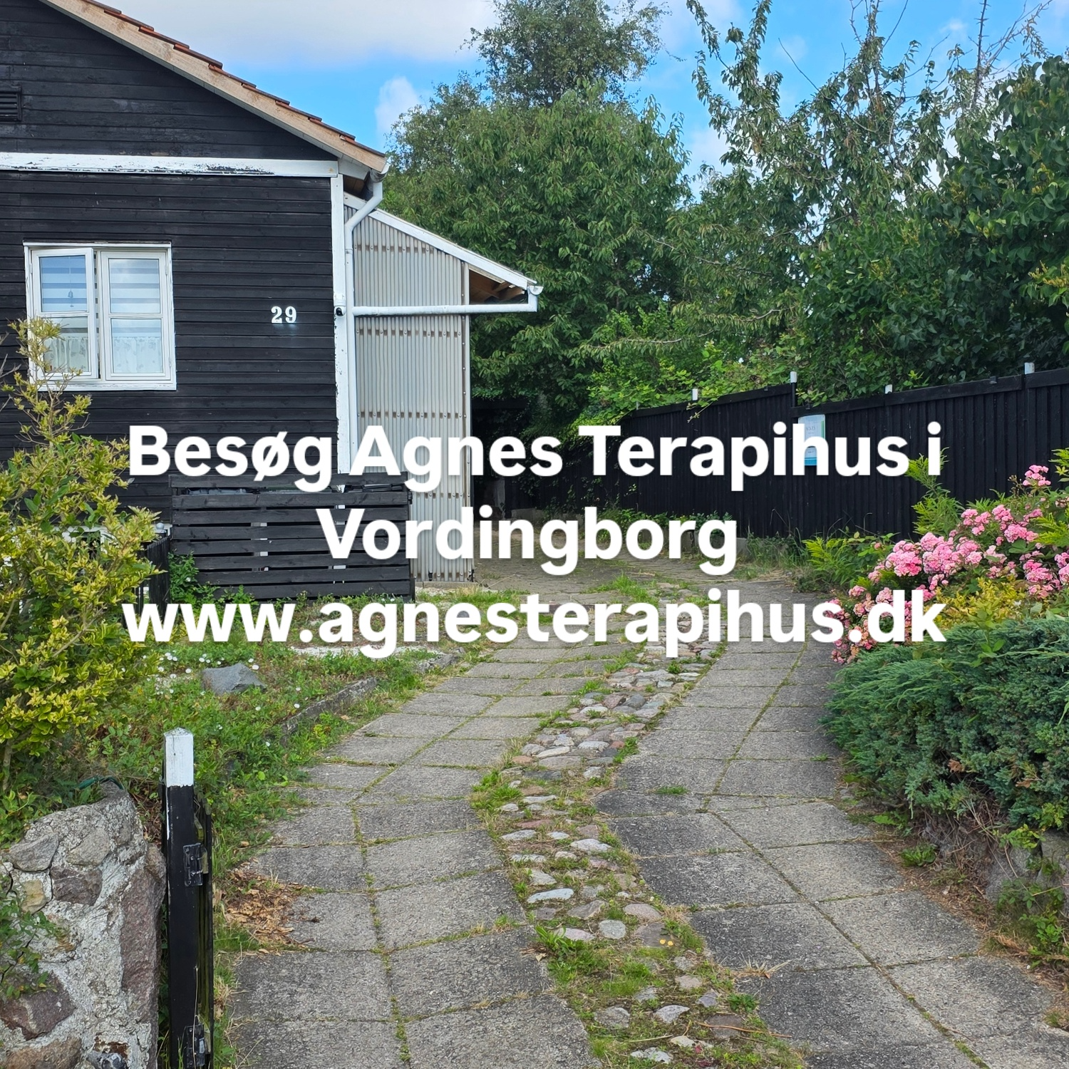 En indgang til Agnes Terapi hus i Vordingborg med stier og blomsterbede.