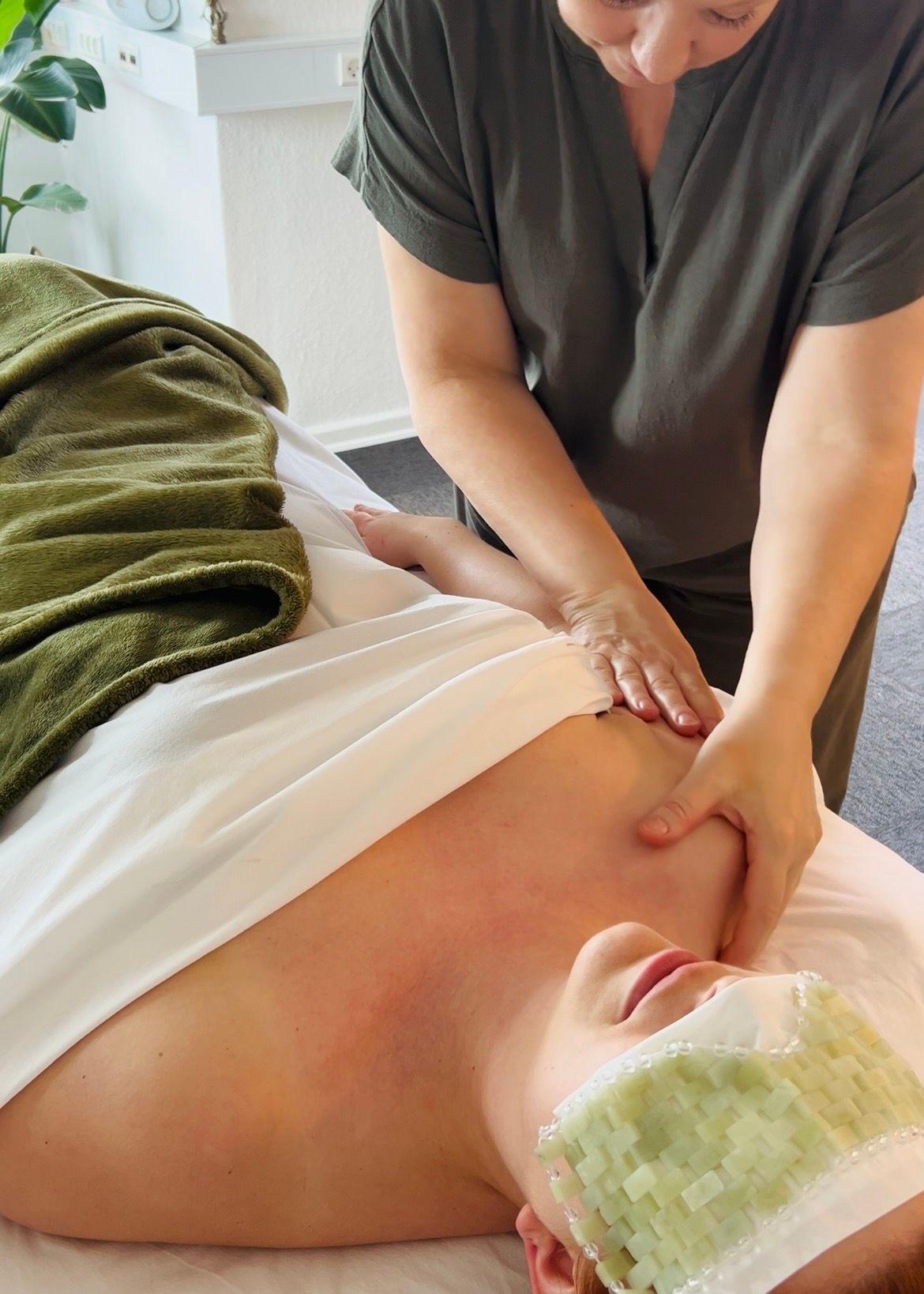 En person får en afslappende massage med en grøn håndklæde på en behandlingsbriks.