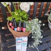 Blomsterkrukke med neglelak og hudplejeprodukter på en bænk i haven.