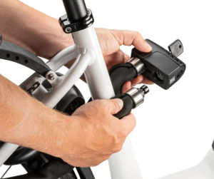 Hånd, der låser en cykel med en lås, mens den holder cyklens ramme.