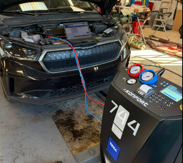Bilen får service med en aircondition-maskine, der viser trykmålinger og diagnosticering.