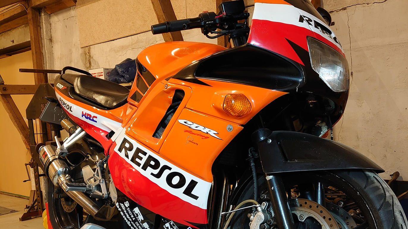 En Repsol motorcykel i en garage med orange og sort farve samt detaljer i rød og hvid.