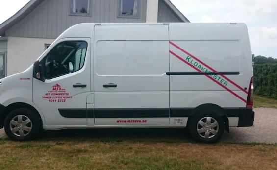 Hvid varevogn med logo og tekst "Kloakmester" parkeret foran et hus.