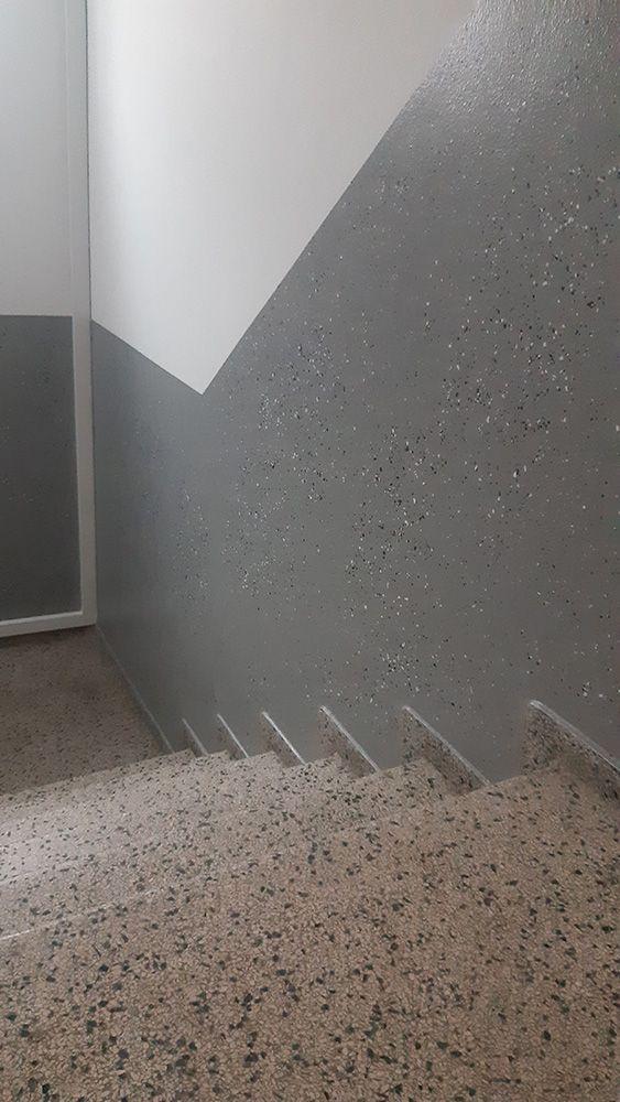 Trappe med grå væg og skridsikre trin, der fører nedad i en bygning.
