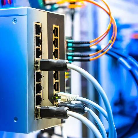 Billede af en netværksswitch med tilsluttede kabler og porte i et teknologisk miljø.